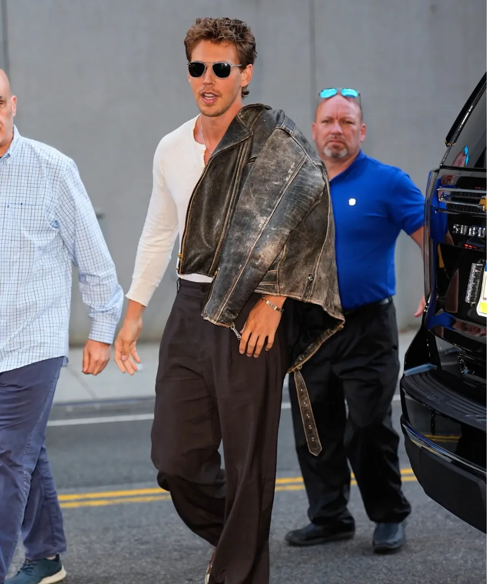 Austin butler with a fin grain distressed brown jacket on his shoulder